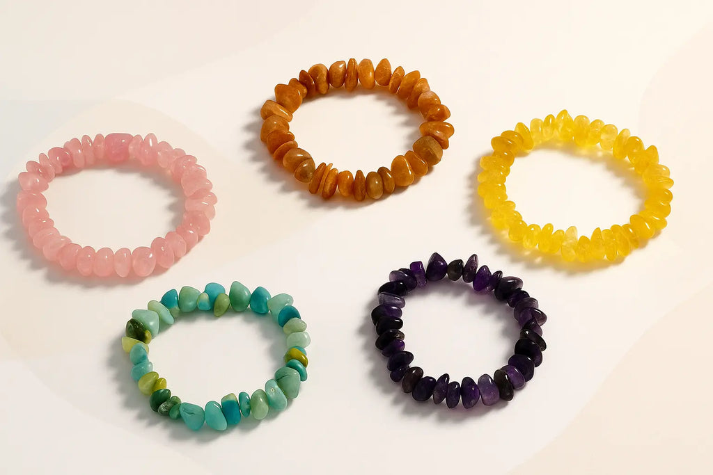 Cinq bracelets en pierres naturelles de lithothérapie présentés à plat sur un fond clair aux formes douces : quartz rose, aventurine, œil de tigre doré, améthyste et citrine. Mise en scène lumineuse au style épuré et élégant.
