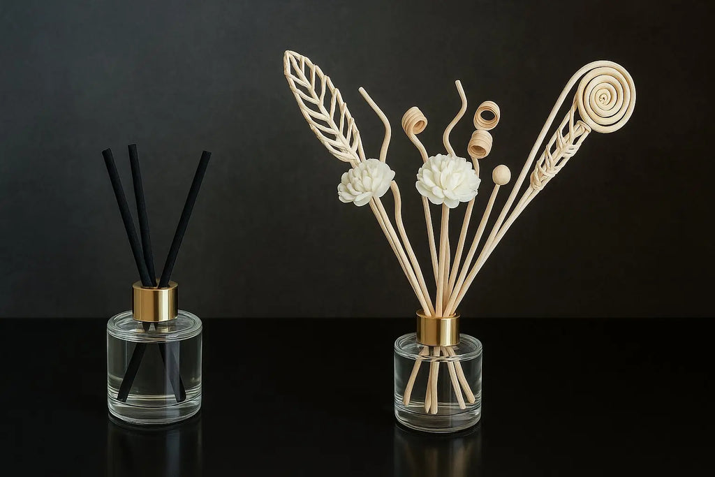 Deux diffuseurs de parfum à tiges, présentés sur des socles roses dans un décor pastel élégant. À gauche, un diffuseur classique avec tiges noires ; à droite, un diffuseur décoratif avec tiges en rotin sculptées et fleurs blanches.