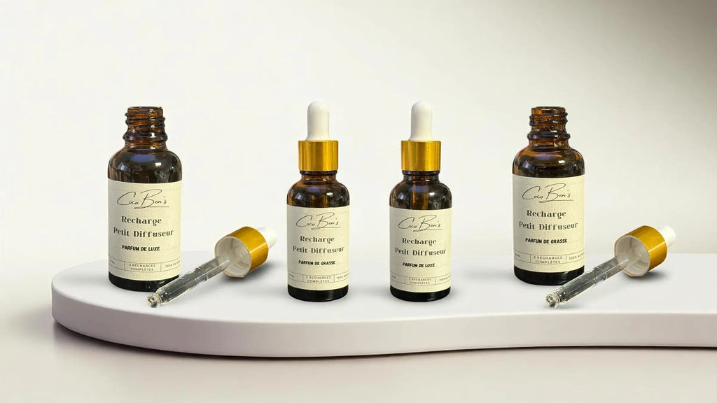 Bannière mettant en scène trois flacons de recharge pour petit diffuseur Coco Ben’s, présentés sur un fond clair et moderne avec des formes graphiques douces en bleu et pêche.